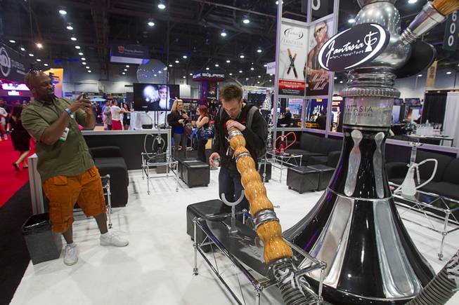 Justin Lawrence of Morgantown, Penn. has his photo taken with a giant hookah during the Nightclub & Bar Convention and Trade Show at the Las Vegas Convention Center Wednesday March 26, 2014.