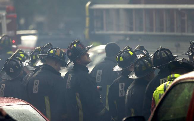 Firefighter look on at the scene of a multi-alarm fire at a four-story brownstone in the Back Bay neighborhood near the Charles River, Wednesday, March 26, 2014, in Boston. 