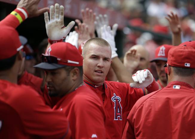 Los Angeles Angels' Mike Trout is congratulated after scoring during an exhibition spring training baseball game against the Chicago White Sox Thursday, March 13, 2014, in Tempe, Ariz.