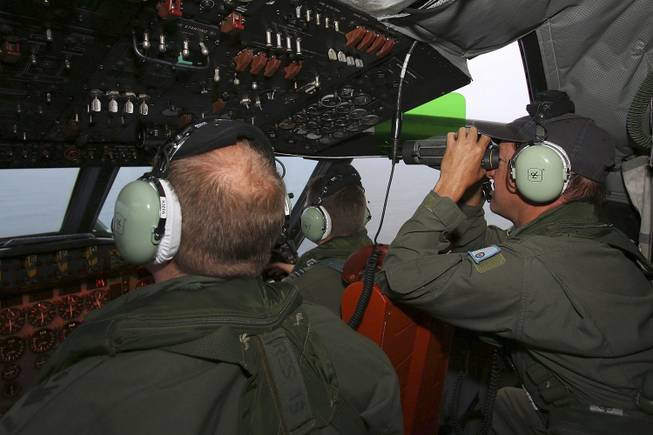 In this Wednesday, March 26, 2014, photo, Flight Engineer Ron Day, right, on board a Royal Australian Air Force AP-3C Orion, searches for the missing Malaysia Airlines Flight 370 in the southern Indian Ocean.