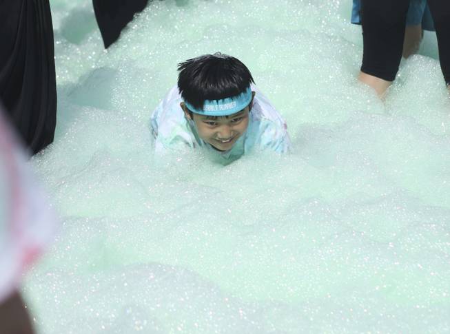 Joshua Hughes plays in the foam at the finish line stage area during the 5k Bubble Run in downtown Las Vegas Saturday, March 29, 2014.