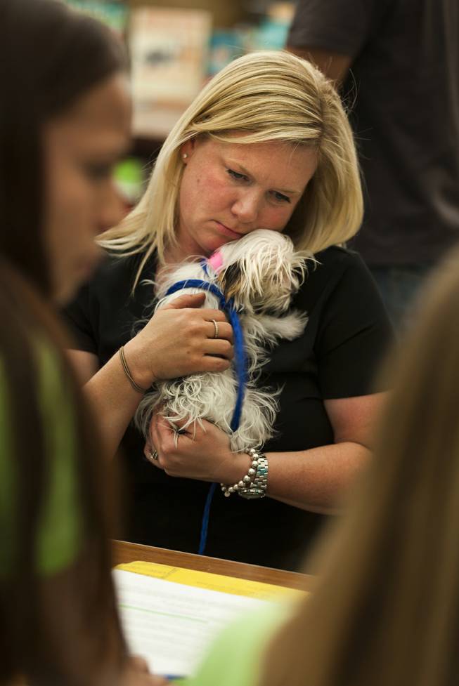 Kristi Liddle cuddles her newly adopted puppy Fia at the Animal Foundation on Wednesday, March 26, 2014.  He is a Maltese/Yorkie mix, 1 of 27 puppies rescued during a fire at the Prince and Princess Pet Shop on Jan. 27.