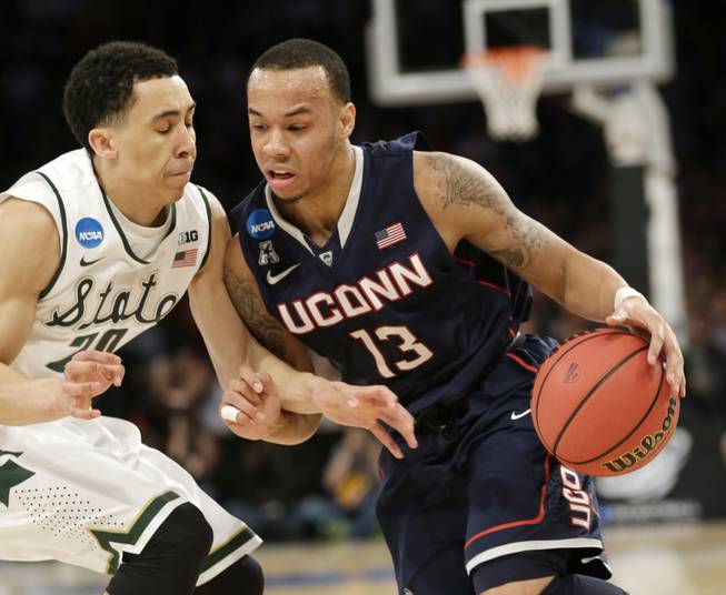 Connecticut's Shabazz Napier, right, moves the ball around Michigan State's Travis Trice in the first half of a regional final at the NCAA college basketball tournament on Sunday, March 30, 2014, in New York. 