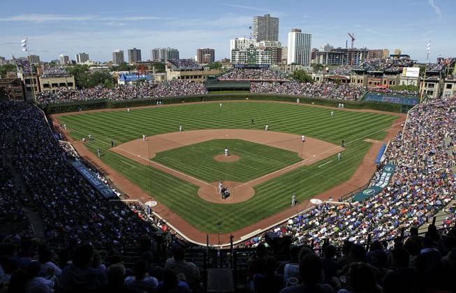 In this Aug. 4, 2013, file photo, the Los Angeles Dodgers play the Chicago Cubs at Wrigley Field in Chicago. Wrigley Field has been the site of so much heartbreak that some fans who spend their whole lives waiting for a winner ask their families, if they can pull it off, to sneak their ashes inside to be scattered in the friendly confines — a final resting place to keep on waiting. But before years turned into decades and decades turned into a century without a World Series title, Wrigley Field was in first time and time again in changing the way we watch baseball and the experience for fans in ballparks around the country. The historic ballpark will celebrate it's 100th anniversary on April 23, 2014.