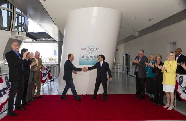 David Codiga, left, Linq executive project director, breaks a bottle of champagne shakes hands with Tariq Shaukat, Caesars Entertainment chief marketing officer, after a christening ceremony for the 550-foot-tall High Roller observation wheel Monday, March 31, 2014. The observation wheel, the tallest in the world, is part of the Linq project, a $550 million development by Caesars Entertainment Corp.