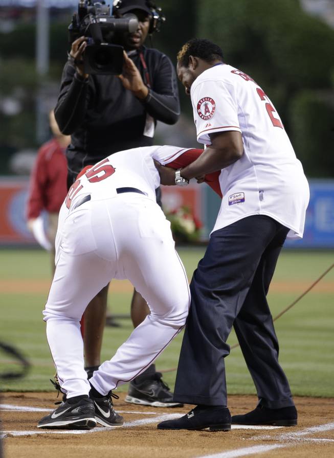 Los Angeles Angels hitting coach Don Baylor, left, is helped up by Vladimir Guerrero after he broke his leg while catching Guerrero's ceremonial first pitch before the Angels' opening day baseball game with the Seattle Mariners on Monday, March 31, 2014, in Anaheim, Calif.