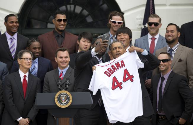 Boston Red Sox designated hitter David "Big Papi" Ortiz takes a selfie with President Barack Obama, holding a Boston Red Sox jersey presented to the president on the South Lawn of the White House in Washington, Tuesday, April 1, 2014, during a ceremony where the president honored the 2013 World Series baseball champion Boston Red Sox. From left are, principal owner John W. Henry, Executive VP and GM Ben Cherington, pitcher Junichi Tazawa, Ortiz, the president, and pitcher Koji Uehara. Top left is infielder Xander Bogaerts.