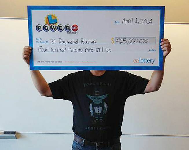 This photo provided by the California Lottery shows Powerball winner B. Raymond Buxton holding a check for $425 million, Tuesday, April 1, 2014, in Sacramento.