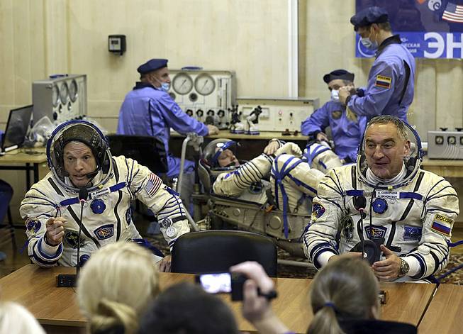 U.S. astronaut Steven Swanson, left, and Russian cosmonaut Alexander Skvortsov, crew members of the mission to the International Space Station, speak with relatives during pre-launch preparations at the Russian-leased Baikonur cosmodrome in Kazakhstan, March 25, 2014. Cosmonaut Oleg Artemyev is at center background. 