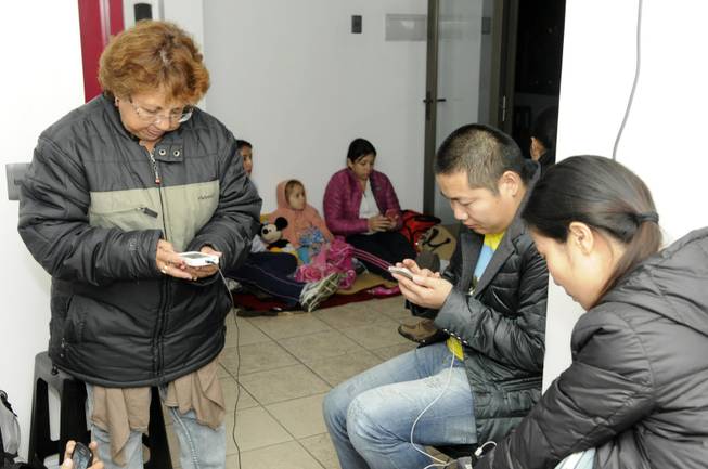 People use their phones on the upper floor of an apartment building located a few blocks from the coast where they gathered to avoid a possible tsunami after an earthquake in Iquique, Chile, Tuesday, April 1, 2014. A powerful magnitude-8.2 earthquake struck off northern Chile on Tuesday night, setting off a small tsunami that forced evacuations along the country's entire Pacific coast.  (AP Photo/Cristian Viveros) NO PUBLICAR EN CHILE