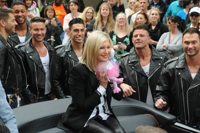 Olivia Newton-John, with Chippendales at the Rio stars Jaymes Vaughan, Matt Marshall, Ryan Stuart, Jon Howes, Nathan Minor and James Davis, makes her way to the Flamingo on Wednesday, April 2, 2014, in Las Vegas.