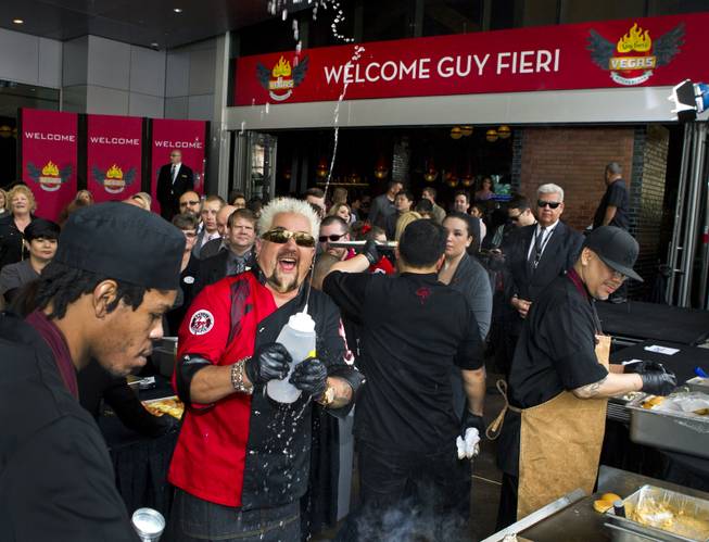 Guy Fieri squirts water in celebration while serving burgers to fans outside his first Las Vegas restaurant, Guy Fieri’s Vegas Kitchen & Bar, on Friday, April 4, 2014, at the Quad.