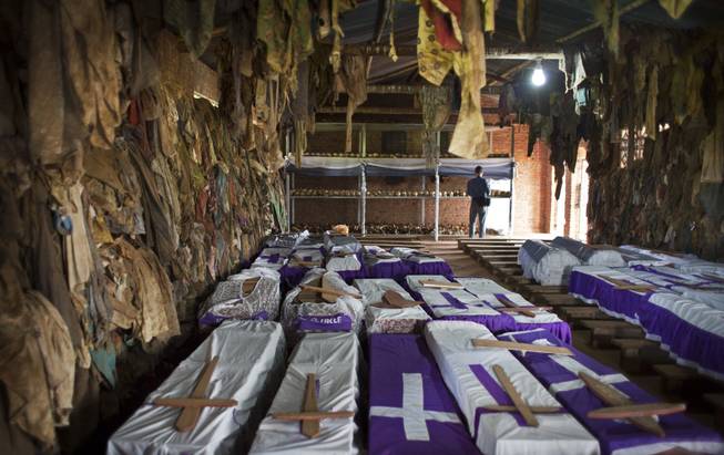 The clothes of some of those who were slaughtered as they sought refuge inside the church hang above coffins containing the remains of multiple victims, as a memorial to the thousands who were killed in and around the Catholic church during the 1994 genocide in Ntarama, Rwanda, Friday, April 4, 2014.