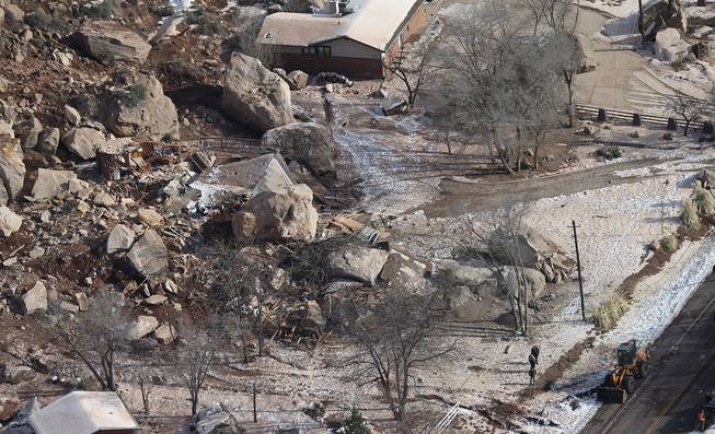 In this Dec. 13, 2013, file photo, officials survey boulders from a rock slide that crushed a home and killed two people, in Rockville, Utah.