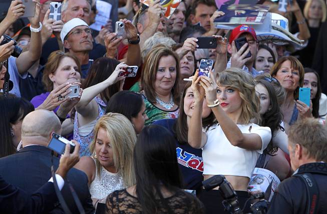 Taylor Swift takes a selfie with a fan as she arrives for the 49th Academy of Country Music Awards show at the MGM Grand Garden Arena Sunday, April 6, 2014.