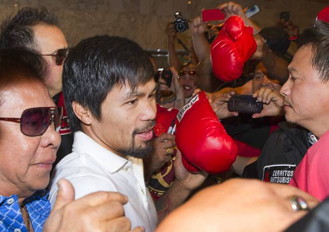 Boxer Manny Pacquiao of the Philippines and his entourage push though media and fans as he arrives at the MGM Grand on Tuesday, April 8, 2014. Pacquiao will challenge undefeated WBO welterweight champion Timothy Bradley at the MGM Grand Garden Arena on Saturday. The fight is a rematch of their bout June 9, 2012, which Bradley won.