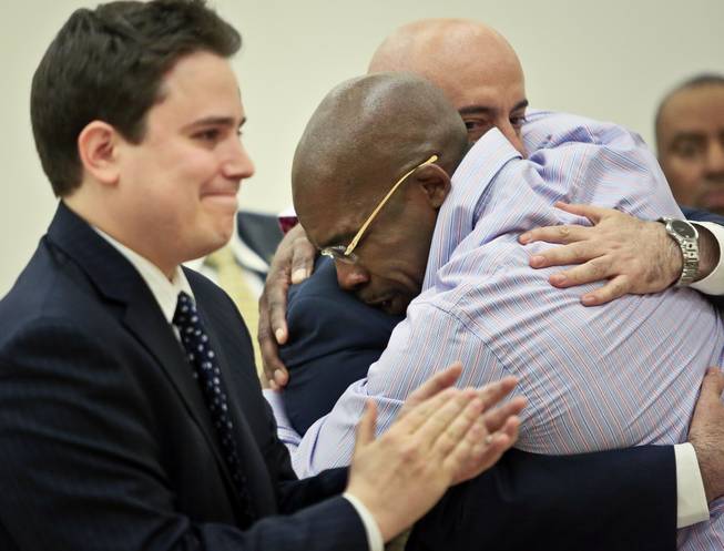 Jonathan Fleming hugs his attorney Anthony Mayol while his other attorney Taylor Koss applaud in Brooklyn's Supreme Court, after a judge declared him a free man on Tuesday April 8, 2014 in New York. Fleming, who spent almost a quarter-century behind bars for murder, was cleared of a killing that happened when he was 1,100 miles away on a Disney World vacation in 1989.