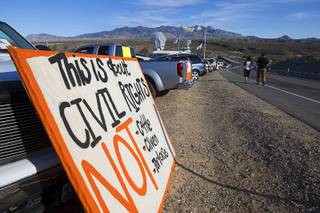 A couple walks past a sign during a protest in support of the Bundy family near Bunkerville Thursday, April 10, 2014.