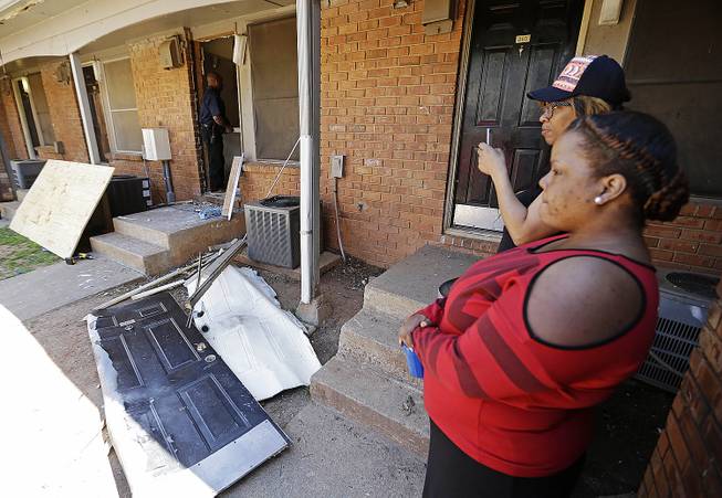 Residents look on as workers repair a neighbor's front door, center, at an apartment complex in Atlanta, Thursday morning, April 10, 2014, where federal agents rescued Frank Arthur Janssen, of Wake Forest, N.C. 