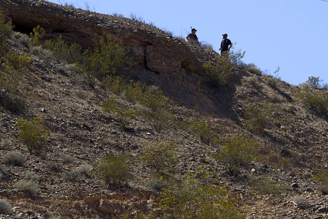 Militia-style volunteers take a position on a hill overlooking a gathering area for Bundy family supporters near Bunkerville Sunday, April 13, 2014. The Bureau of Land Management halted their roundup of Bundy family cattle under an agreement reached Saturday.