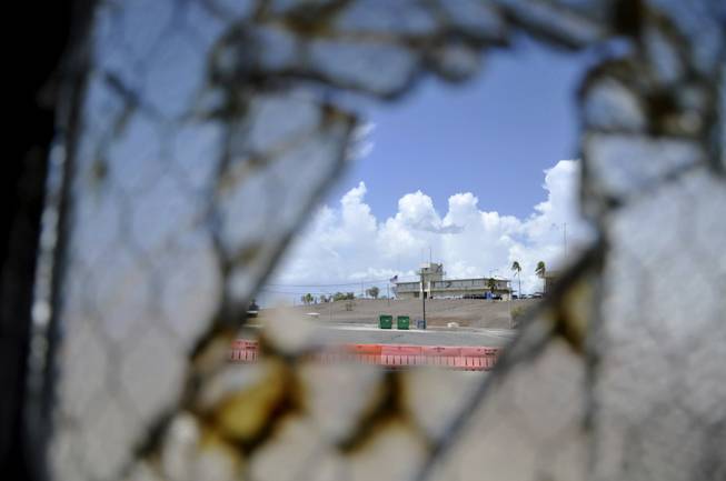 In this Aug. 23, 2013, file photo reviewed by the U.S. Department of Defense, one of Guantanamo Bay's two courthouses is seen through a broken window at Camp Justice at the Guantanamo Bay U.S. Naval Base, Cuba. 