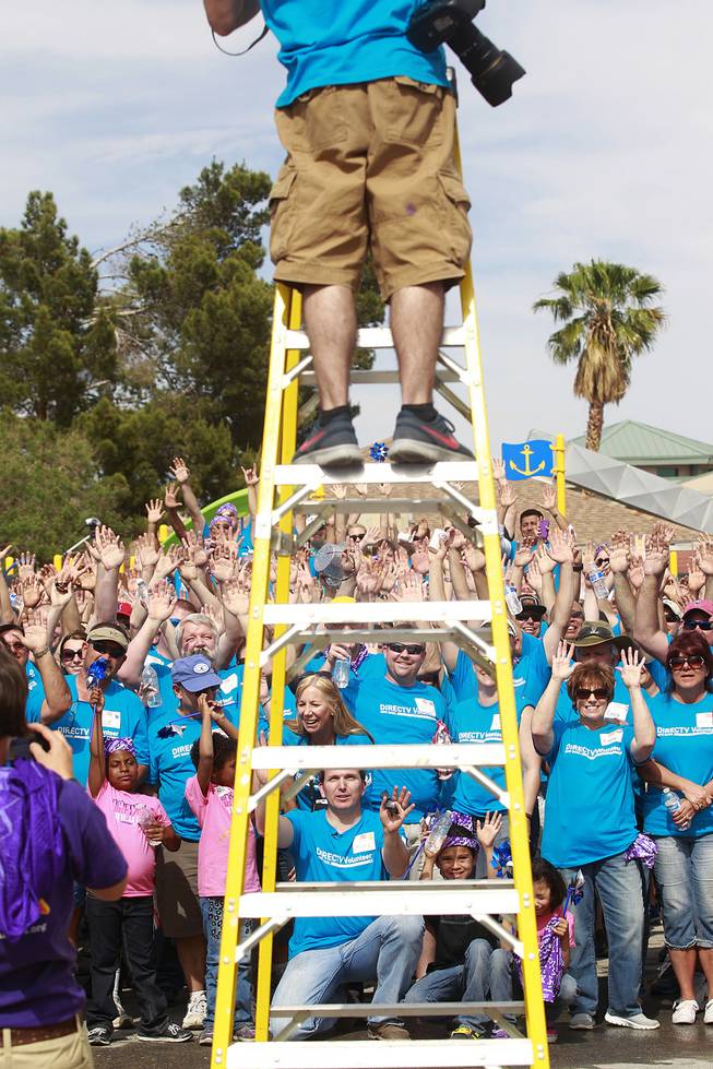 Volunteers cheer while having their photo taken after building a KaBoom playground for Child Haven Tuesday, April 15, 2014. Clark County Department of Family Services and Chicanos Por La Causa teamed up with volunteers from DirectTV and local businesses to rebuild the playground that was closed in 2012.