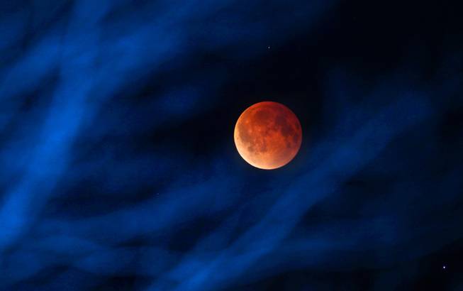 The moon glows a red hue during a total lunar eclipse Tuesday, April 15, 2014, as seen from the Milwaukee area. Tuesday's eclipse is the first of four total lunar eclipses that will take place between 2014 to 2015. (AP Photo/Milwaukee Journal-Sentinel, Mike De Sisti)