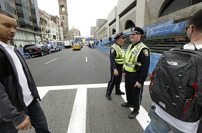Boston Police, center, stand near the finish line of the Boston Marathon, behind, on Boylston Street, Monday, April 14, 2014, in Boston. 