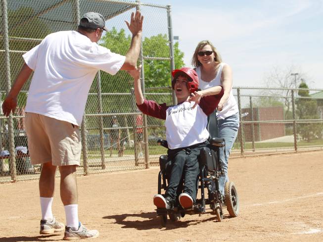 Ben Dauterive from the Loan Writers gets a high five as his mom Kim Dauterive helps him across home plate as Silverado Little League hosts Challenger Little League day Saturday, April 12, 2014.