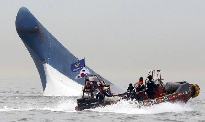 South Korean coast guard officers try to rescue passengers from a ferry sinking in the water off the southern coast near Jindo, south of Seoul, South Korea, Wednesday, April 16, 2014. The ferry carrying 459 people, mostly high school students on an overnight trip to a tourist island, sank off South Korea's southern coast on Wednesday, leaving nearly 300 people missing despite a frantic, hours-long rescue by dozens of ships and helicopters. At least four people were confirmed dead and 55 injured. (AP Photo/Yonhap) KOREA OUT