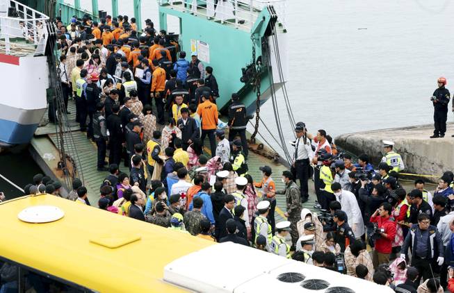 Rescued passengers are escorted by members of a rescue team upon their arrival at a port in Jindo, south of Seoul, South Korea, Wednesday, April 16, 2014. More than 100 people were still unaccounted Wednesday several hours after a ferry carrying 476, most of them high school students, sank in cold waters off South Korea's southern coast, killing at least two and injuring 14, officials said.