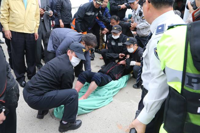A rescued passenger from a ferry sinking off South Korea's southern coast, is carried by police and rescue teams on his arrival at Jindo port in Jindo, south of Seoul, South Korea, Wednesday, April 16, 2014. Dozens of rescue boats and helicopters are scrambling to save more than 470 people, including many high school students, caught on a ferry sinking off South Korea's southern coast, officials said. There are no immediate reports of causalities.