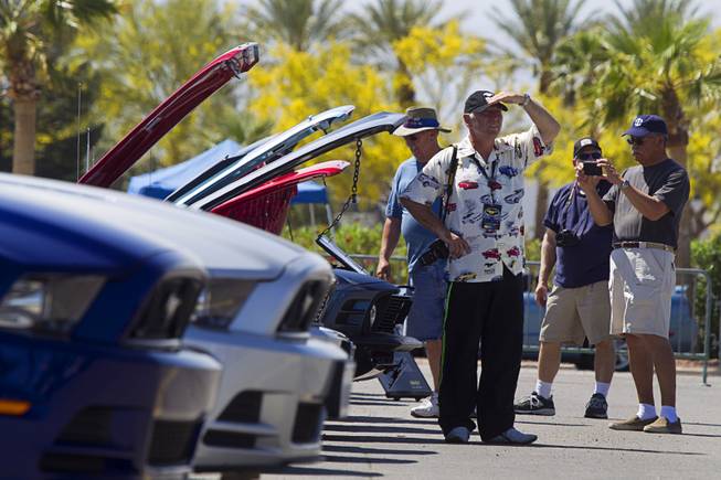Paul Metcalfe, center, of New Zealand looks over classic Mustangs during the Mustang 50th Birthday Celebration at the Las Vegas Motor Speedway Thursday, April 17, 2014.
