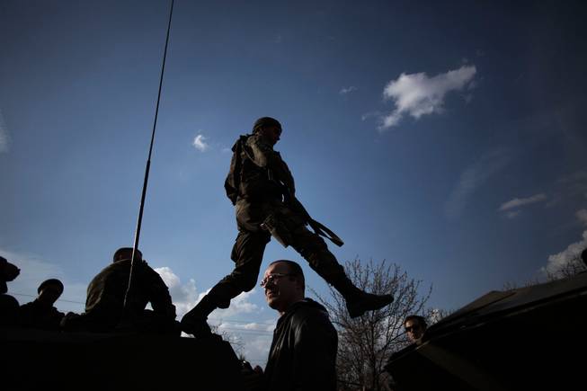 A soldier from the Ukrainian Army jumps on top of an armored vehicle, as they are blocked by people on their way to the town of Kramatorsk on Wednesday, April 16, 2014. Pro-Russian insurgents commandeered six Ukrainian armored vehicles along with their crews and hoisted Russian flags over them Wednesday, dampening the central government's hopes of re-establishing control over restive eastern Ukraine. 