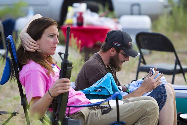 Chris Shelton of Las Vegas interacts with his 1-week-old son as his mother Shelley Shelton holds his rifle during a Bundy family "Patriot Party" near Bunkerville Friday, April 18, 2014. The Bundy family organized the party to thank people who supported rancher Cliven Bundy in his dispute with the Bureau of Land Management.