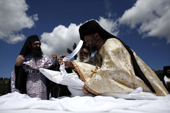 A Greek Orthodox priest wraps an icon of the body of Jesus with a sheet during a Good Friday reenactment  of Christ being taken down from the crucifix, at the Penteli Monastery, near Athens, on Friday, April 18, 2014. More than 250 million Orthodox Christians worldwide will celebrate Easter this year on Sunday, April 20. 