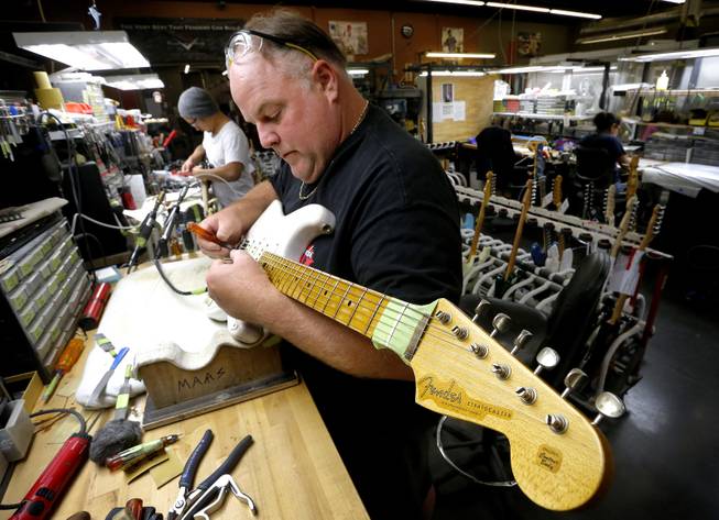 A finished Fender Stratocaster is adjusted by Kenneth Maas in the Fender Custom Shop in Corona, Calif. on Tuesday, Oct. 15, 2013. Leo Fender developed the instrument in a small workshop in Fullerton, Calif. six decades ago.
