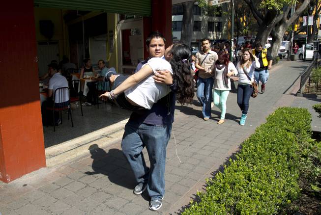 A woman is carried at the Juarez neighborhood after a strong earthquake jolted Mexico City, Friday, April 18, 2014. The powerful magnitude-7.2 earthquake shook central and southern Mexico but there were no early reports of major damage or casualties. 