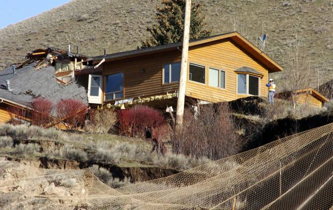 A worker inspects damage to a house at the top of a slow-motion landslide in Jackson, Wyo., on Saturday, April 19, 2014.