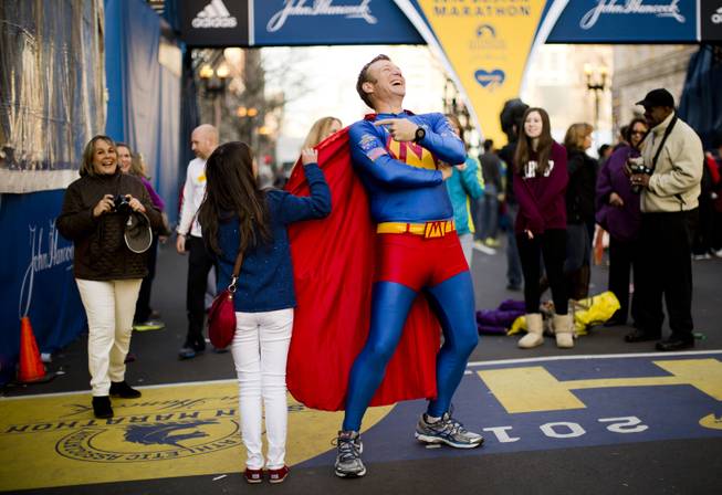 Trent Morrow of Sydney, Australia, also know as Marathon Man laughs as Andrea Olivo of Venezuela tugs on his cape as she has her photo made ahead of Monday's 118th Boston Marathon, Sunday, April 20, 2014, in Boston. Morrow says Monday's marathon will be his 200th run since Jan. 1, 2013. 