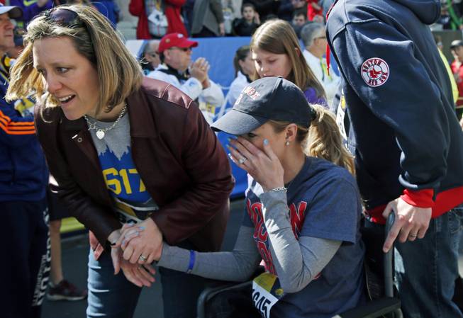 Survivor Rebekah Gregory DiMartino, center, wipes tears as she is led in her wheelchair after crossing the finish line of the Boston Marathon Tribute Run in Boston, Saturday, April 19, 2014.