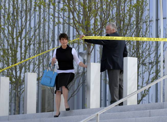 Authorities lead a person out as police investigate a shooting inside the Federal Courthouse, Monday, April 21, 2014, in Salt Lake City. A U.S. marshal shot and critically wounded a defendant on Monday in a new federal courthouse after the man rushed the witness stand with a pen at his trial in Salt Lake City, authorities said.