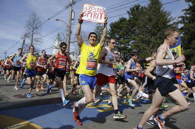 Runners in the first wave of 9,000 cross the start line of the 118th Boston Marathon Monday, April 21, 2014 in Hopkinton, Mass.