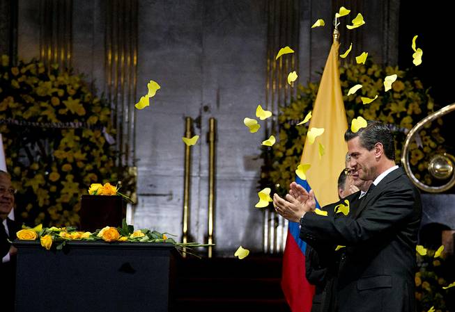 Yellow paper butterflies fall as Mexico's President Enrique Pena Nieto stands next to the urn containing the ashes of Colombian Nobel Literature laureate Gabriel Garcia Marquez during the authors homage at the Palace of Fine Arts in Mexico City, Monday, April 21, 2014. 