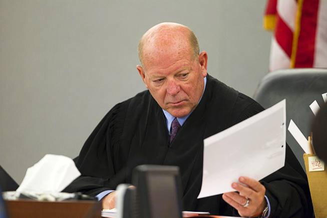 Judge James Bixler looks at an accident photo during sentencing for Nyakueth Tear of Salt Lake City, Utah at the Regional Justice Center Tuesday, April 22, 2014. Tear struck eight pedestrians with her car in the street outside of a North Las Vegas church in August 2013 and fled the scene.