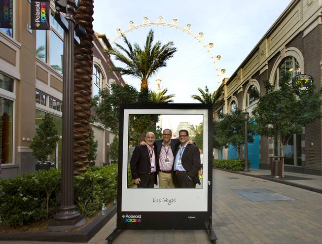 Sandy Letchner, Warren Struhl and Todd Fine stand behind by a large frame outside their Polaroid Fotobar and Polaroid Museum on Wednesday, April 23, 2014, at the Linq.