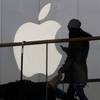 In this Dec. 23, 2013, file photo, a woman using a phone walks past Apple's logo near its retail outlet in Beijing. Apple reported its quarterly earnings on Wednesday, April 23, 2014.