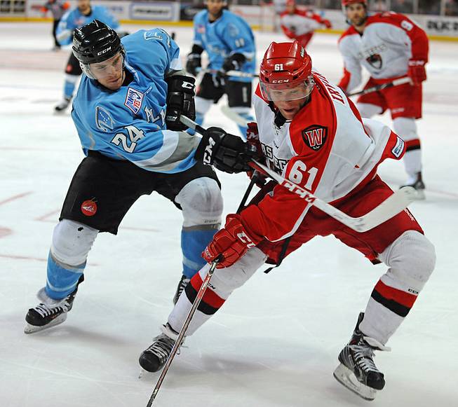 Alaska Aces defenseman John Ramage (24) uses his stick to slow down Wranglers center Geoff Irwin (61) as they both chase the puck into a corner during the third period of Game 4 of a first-round ECHL playoff matchup Friday, April 25, 2014, at Orleans Arena.