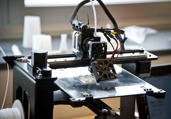 A 3-D printer at Westtown High School prints out parts for an artificial hand designed by Westtown engineering students for eight-year-old Steele Songle, April 18, 2014, in West Chester, Pa.