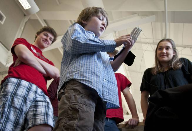 Eight-year-old Steele Songle tries on an artificial hand designed by engineering students at Westtown High School, April 18, 2014, in West Chester, Pa. In the background are engineering students Annika Cole and Alex Hunes, who helped with the design.